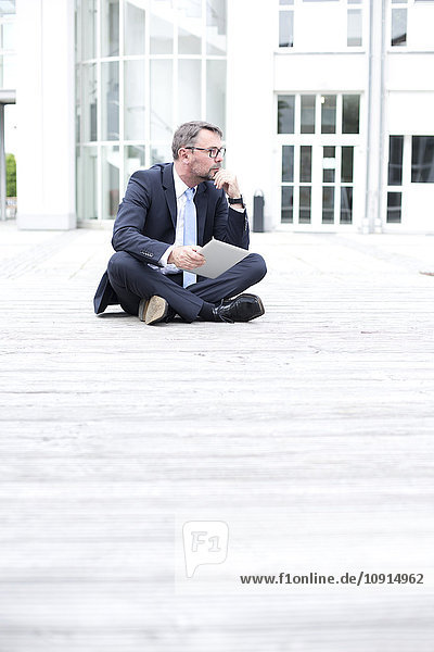 Geschäftsmann im Freien sitzend mit digitalem Tablett