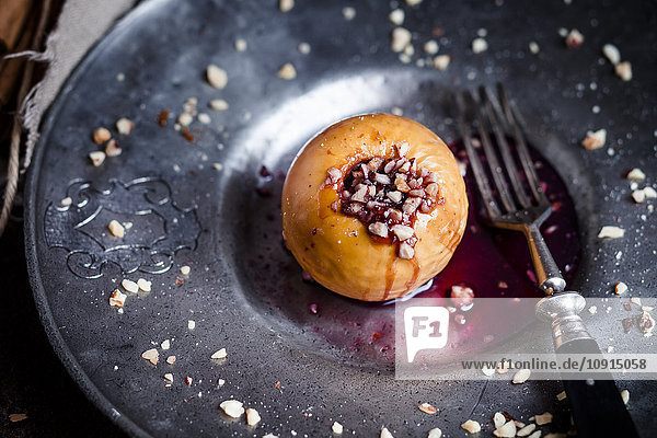 Baked apple with nut- and red jam filling on tin plate