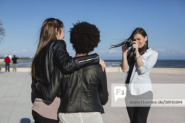 Young woman with camera photographing friends