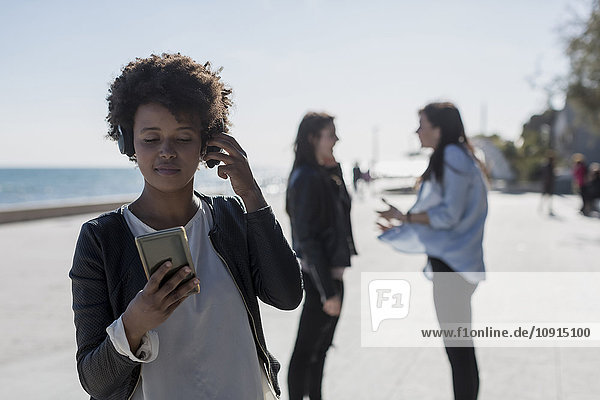 Junge Frau hört Musik mit Smartphone
