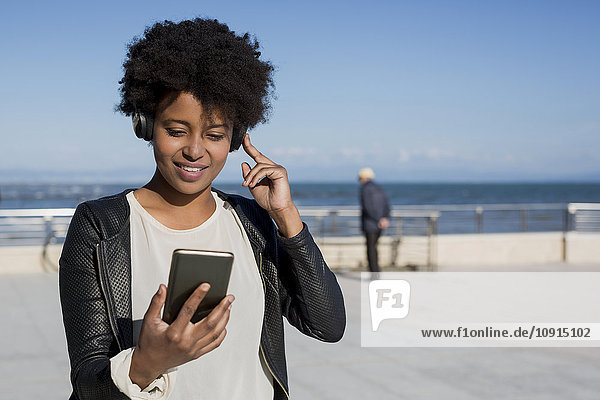 Junge Frau hört Musik mit Smartphone