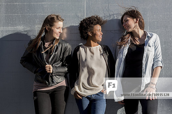 Drei junge Frauen  die sich an die Wand lehnen.