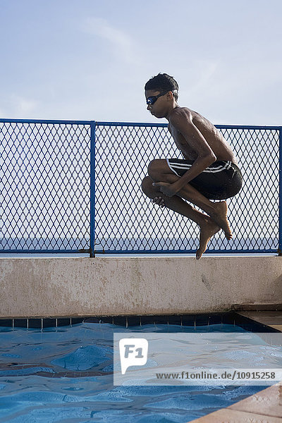 Teenager,  der einen Kanonenkugel-Tauchgang ins Schwimmbad macht.