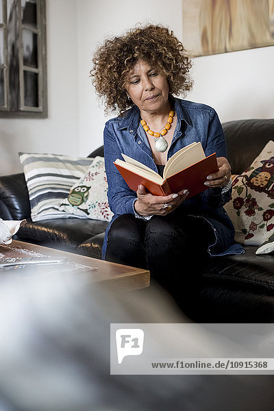 Woman sitting on couch reading book