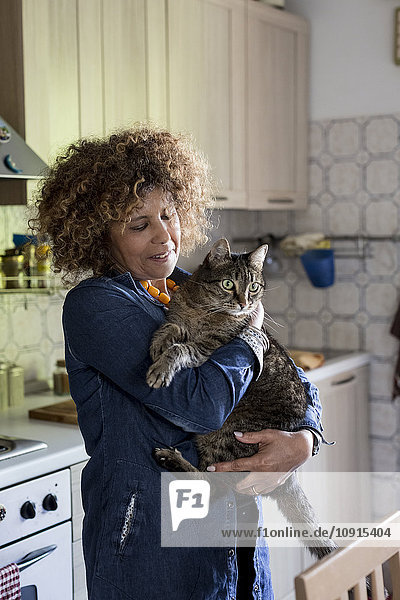 Woman cuddling with cat in kitchen