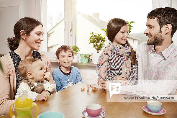 Happy family of five sitting at table at home