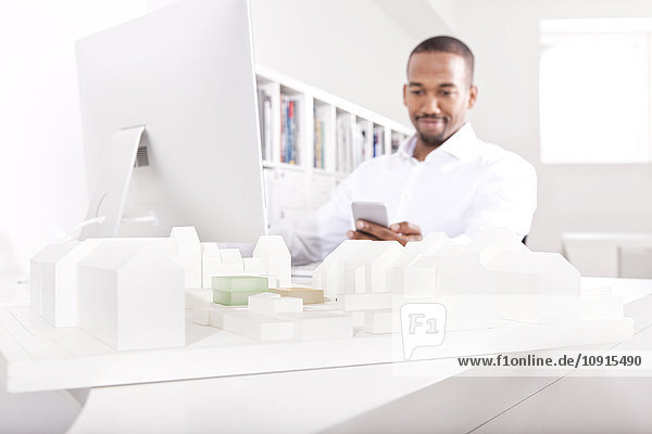 Architectural model on a desk at office with man looking at his smartphone in the background