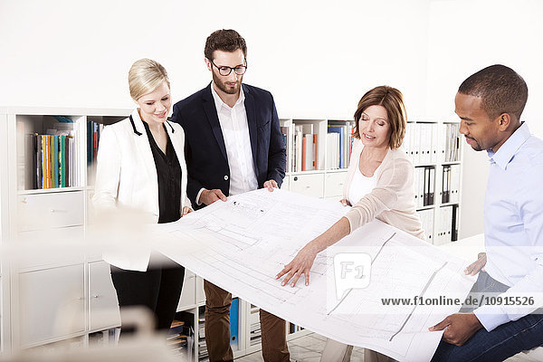 Four colleagues discussing construction plan in an office