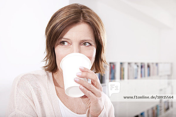 Portrait of woman drinking coffee to go in the office