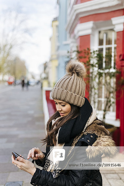 UK  London  Notting Hill  junge Frau beim Blick auf ihr Smartphone