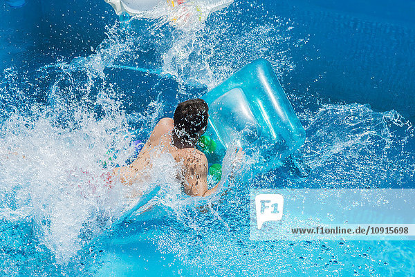 Mann im Pool auf Luftmatratze  sich bewegend  Wasserspritzer