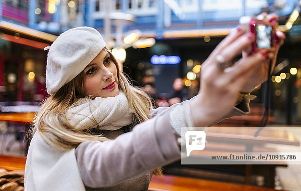 Young woman wearing beret taking selfie with digital camera