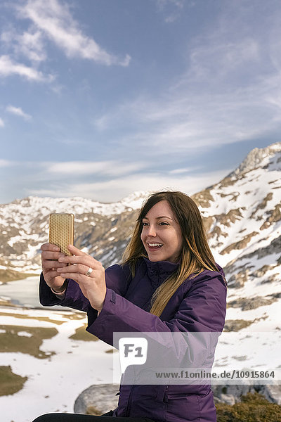 Spanien  Asturien  Somiedo  lächelnde Frau  die einen Selfie in den Bergen nimmt