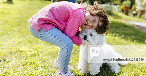 Kleines Mädchen mit ihrem Hund auf einer Wiese