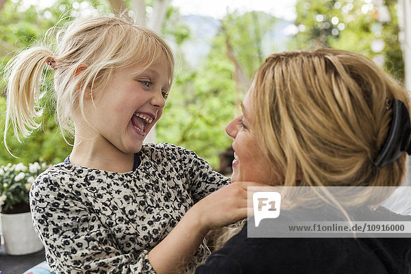 Lachendes kleines Mädchen von Angesicht zu Angesicht zu ihrer Mutter