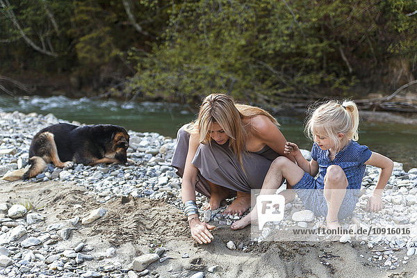 Mutter und ihre kleine Tochter spielen zusammen am Flussufer.