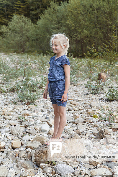 Smiling little girl standing on a rock in nature