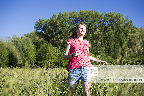 Happy teenage girl running on a meadow