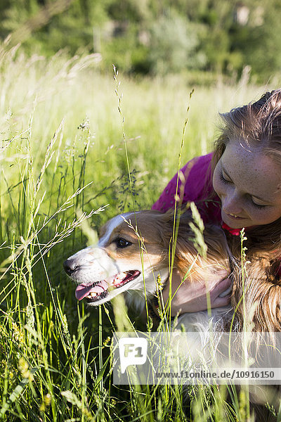 Italien  Lecco  Teenagermädchen mit ihrem Hund auf einer Wiese