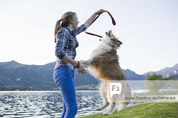 Italien  Lecco  Teenagermädchen spielt mit ihrem Hund am Seeufer