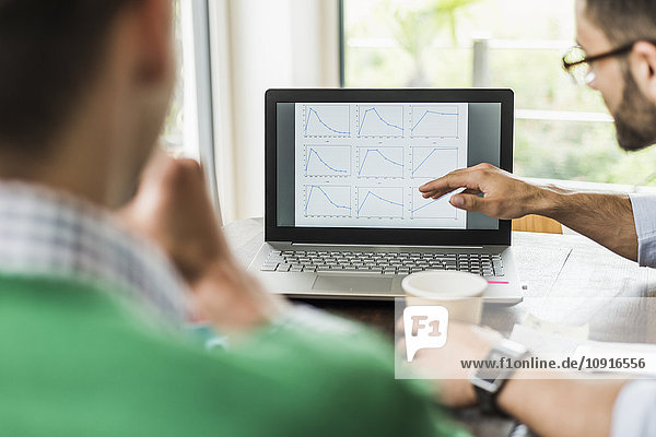 Zwei Geschäftsleute analysieren Liniendiagramme auf dem Laptop-Monitor