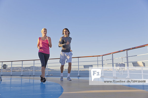 Junges Paar joggt auf dem Schiffsdeck eines Kreuzfahrtschiffes  Mittelmeer