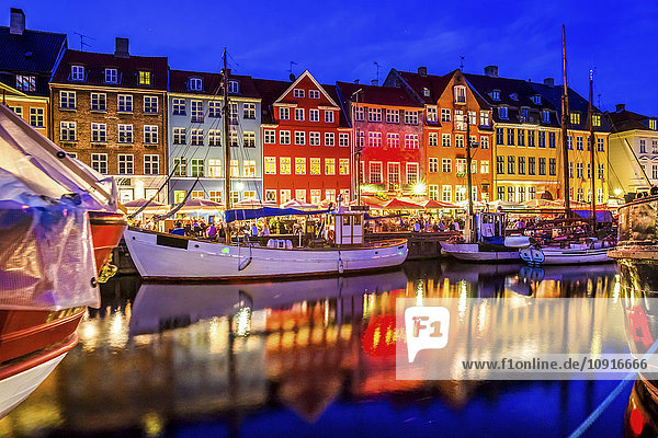 Dänemark  Kopenhagen  Blick auf historische Boote und Häuserzeile in Nyhavn am Abend