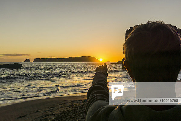 Neuseeland  Wanganui  Rückansicht des Mannes am Strand mit Blick auf die aufgehende Sonne