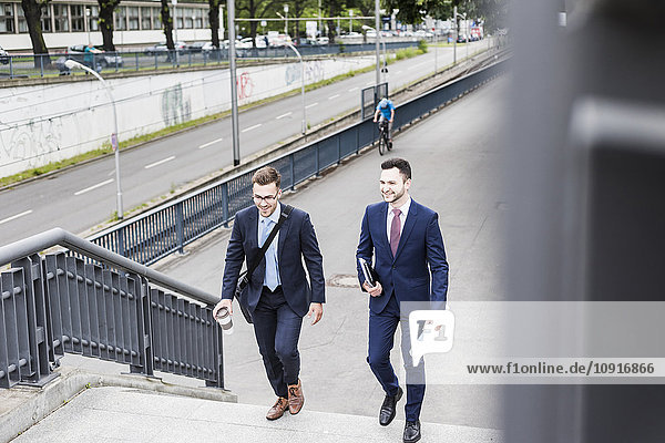 Zwei junge Geschäftsleute  die zusammen in der Stadt spazieren gehen.