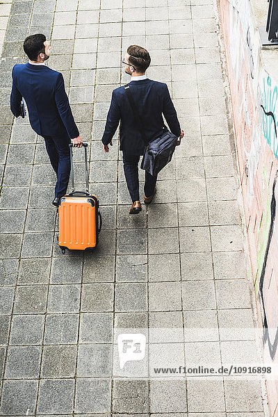 Businessmen on business trip walking with wheeled luggage