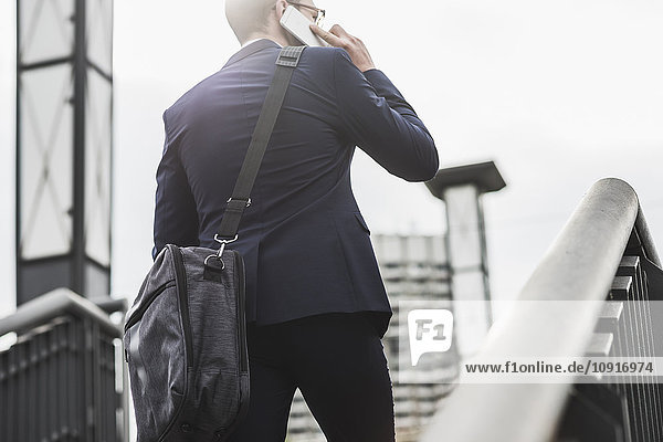Young businessman standing at railing  using smart phone