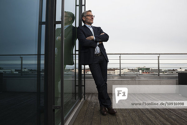 Successful businessman standing on office terrace looking pleased