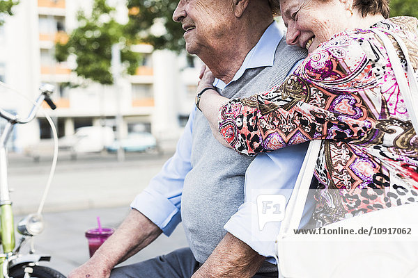 Seniorin mit Kopf auf der Schulter ihres Mannes auf einer Bank sitzend