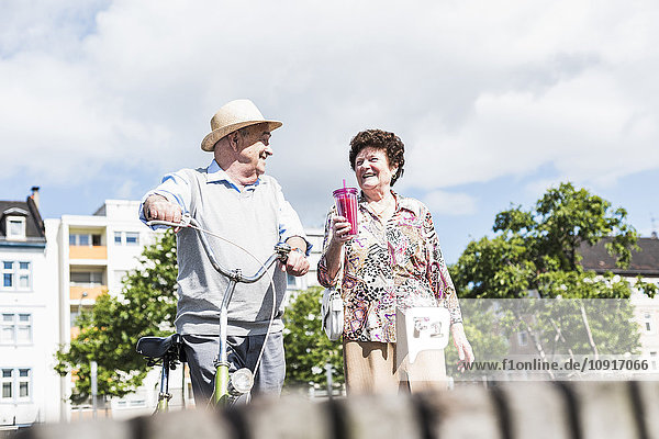 Glückliches Seniorenpaar mit Fahrrad und Erfrischungsgetränk