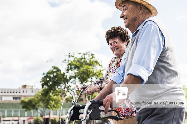 Happy senior couple with bicycle and wheeled walker