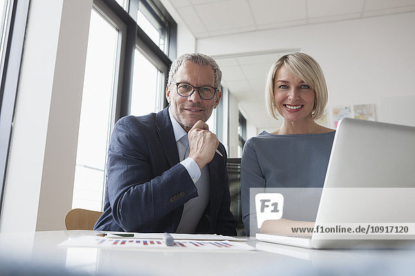 Businessman and woman working together in office using laptop