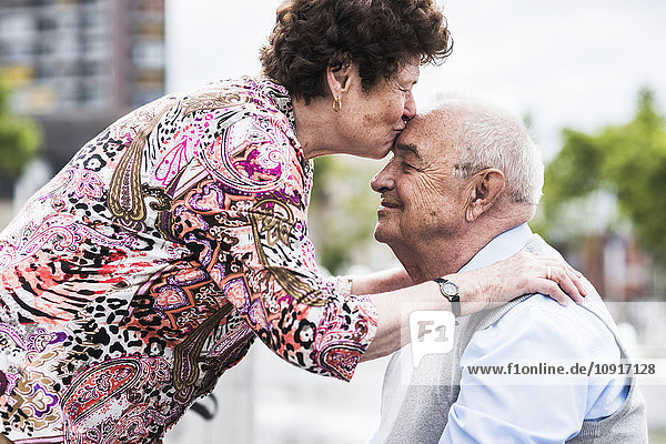 Seniorin  die ihren Mann küsst.