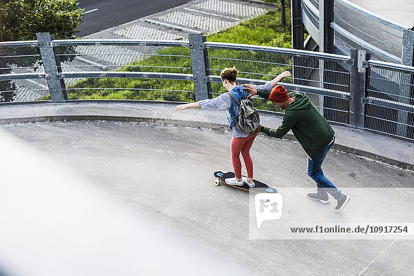 Junges Paar mit Skateboard im Parkhaus