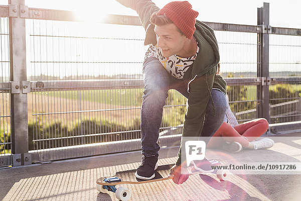 Junger Mann fährt Skateboard auf Parkebene