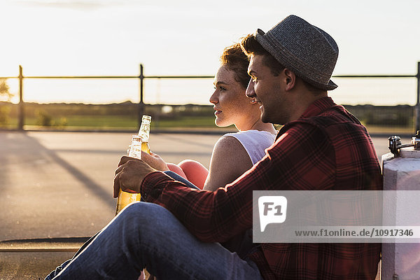 Junges Paar mit Bierflaschen genießt den Sonnenuntergang