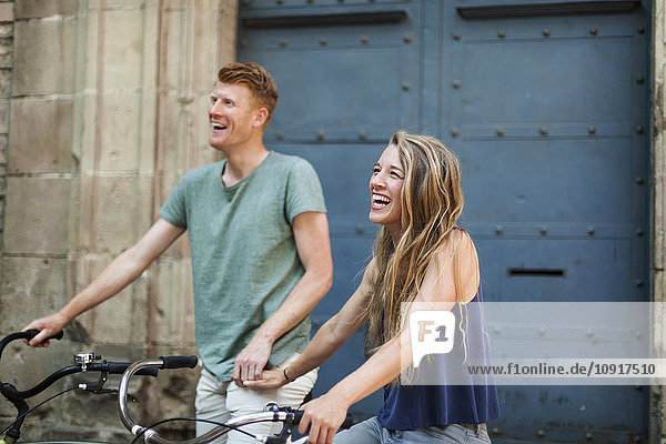 Porträt der lachenden Frau mit dem Fahrrad und ihrem Freund im Hintergrund