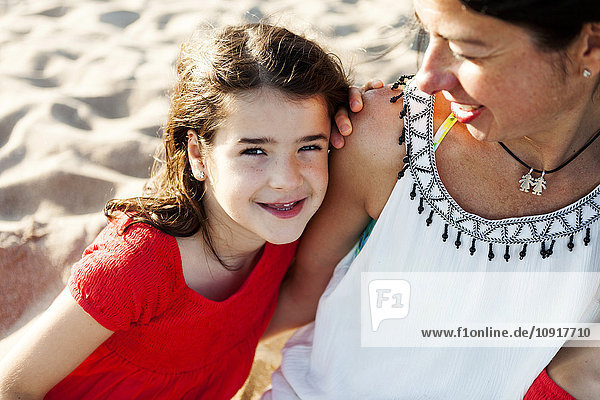 Porträt eines glücklichen kleinen Mädchens neben ihrer Mutter am Strand