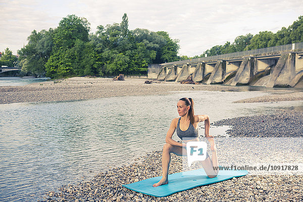 Frau beim Yoga am Flussufer