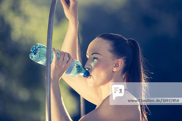 Sportliche junge Frau trinkt Wasser aus der Flasche