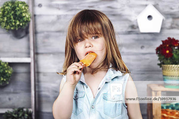 Porträt eines kleinen Mädchens,  das Eis am Stiel isst.