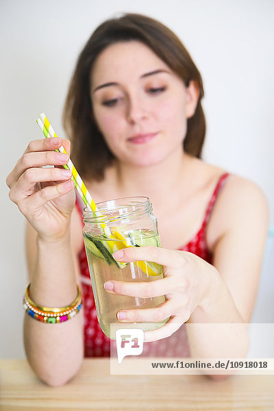 Frau hält ein Glas Entgiftungswasser mit Zitrone und Gurke in der Hand