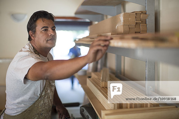 Mann mit Holzrahmen im Regal in der Leinwandwerkstatt
