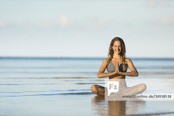 Thailand  smiling woman meditating on beach