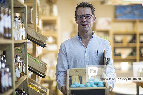 Portrait of shoppkeeper in health shop holding crate