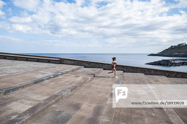 Teenager-Mädchen läuft auf einer Treppe am Ozean